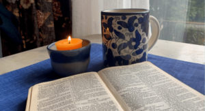 image of burning candle, mug of tea and an open bible