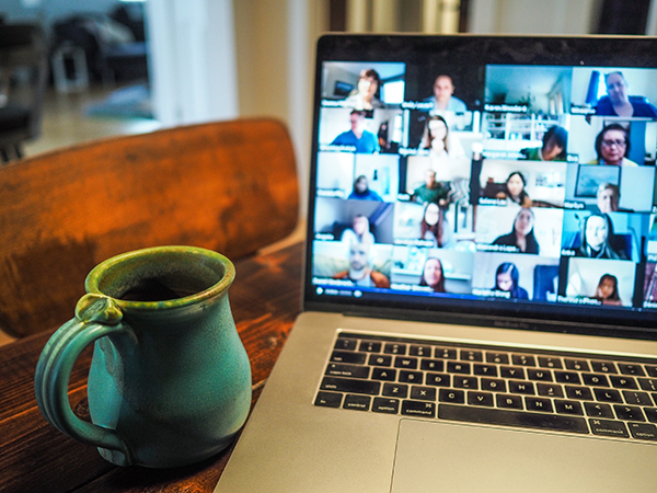 photo of a zoom meeting on a laptop, a mug of tea on table top.