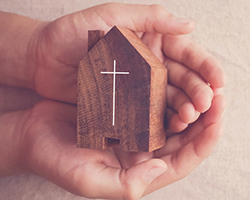 hands holding a wooden block shaped like a church